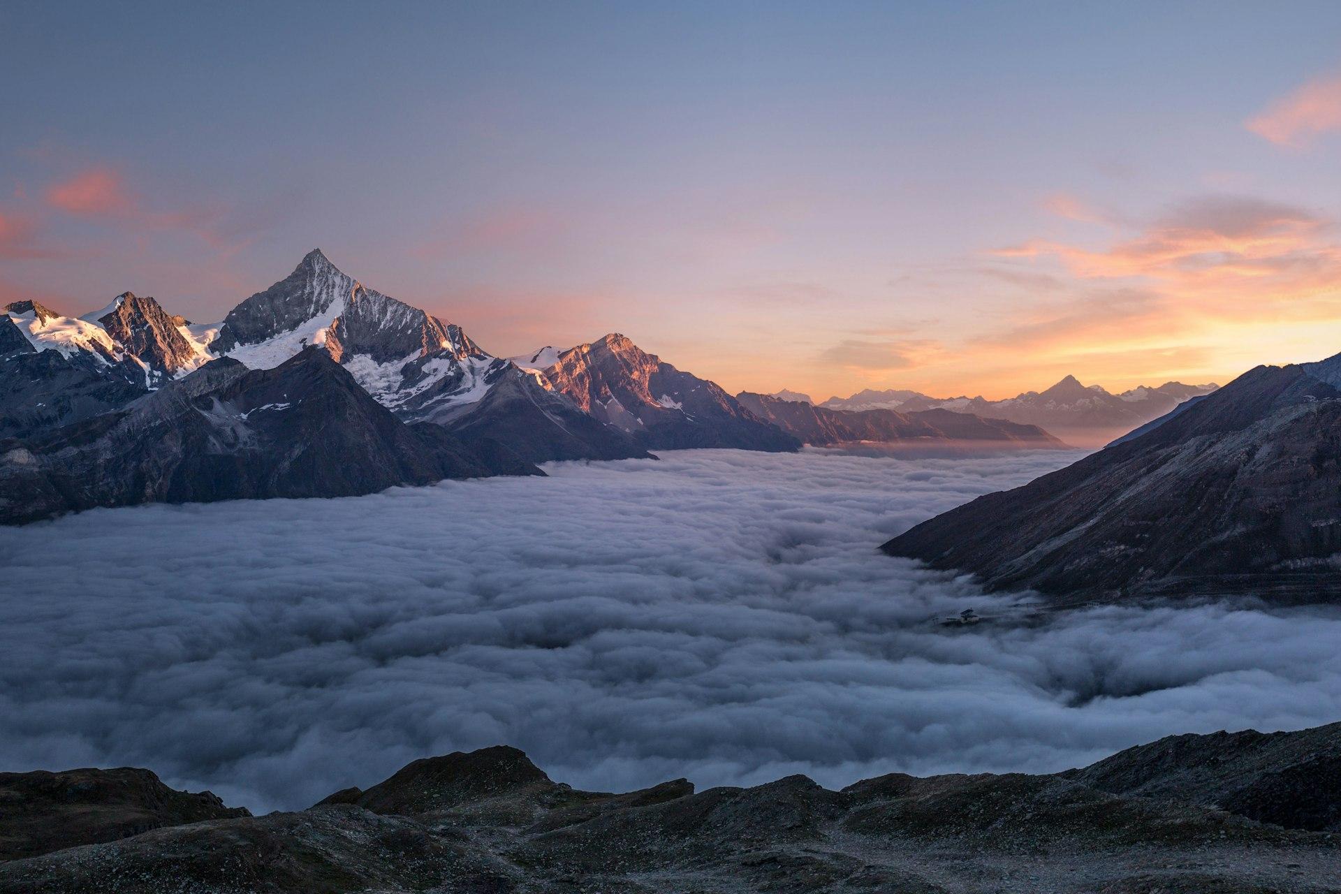 Picos de montanha cobertos de neve sobre um vale glaciar ao amanhecer